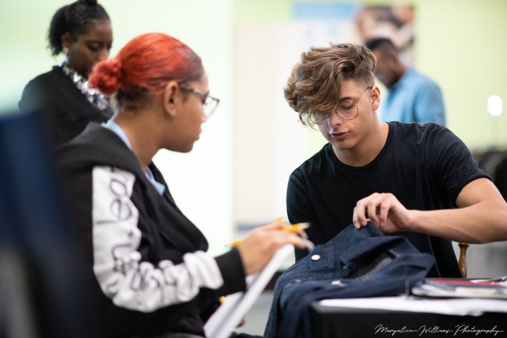 Two teenagers looking at a dark denim jacket, part of Youth Challenge Day 1.